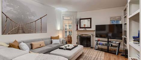 A living room with a sofa, coffee table, TV, fireplace, and bookshelves.