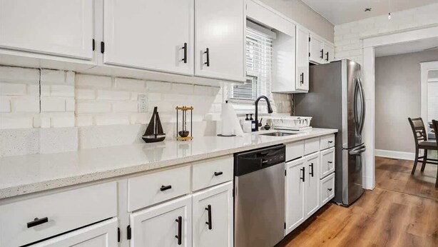Una cocina moderna con armarios blancos, electrodomésticos de acero inoxidable y lavavajillas.