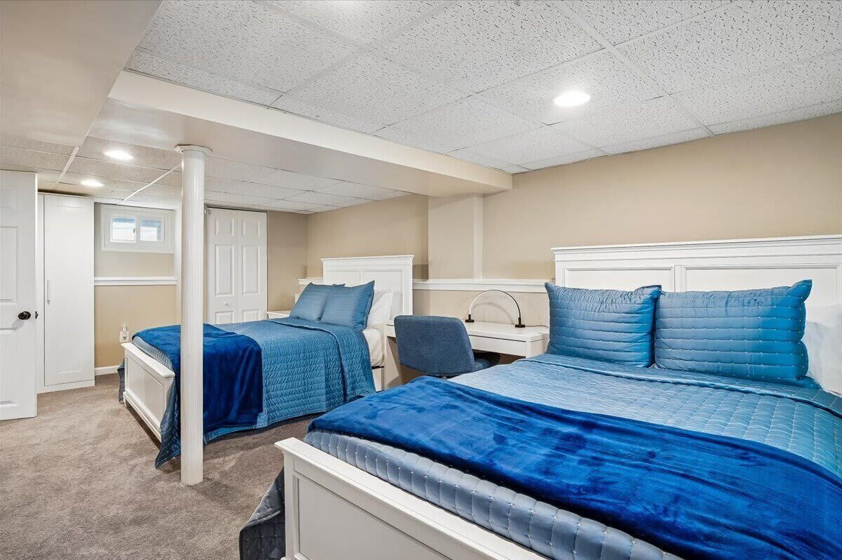 A bedroom with two beds, a desk, and a chair.