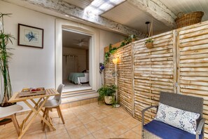 A room with a wooden wall, a wicker chair, a table with a tray, and a potted plant.