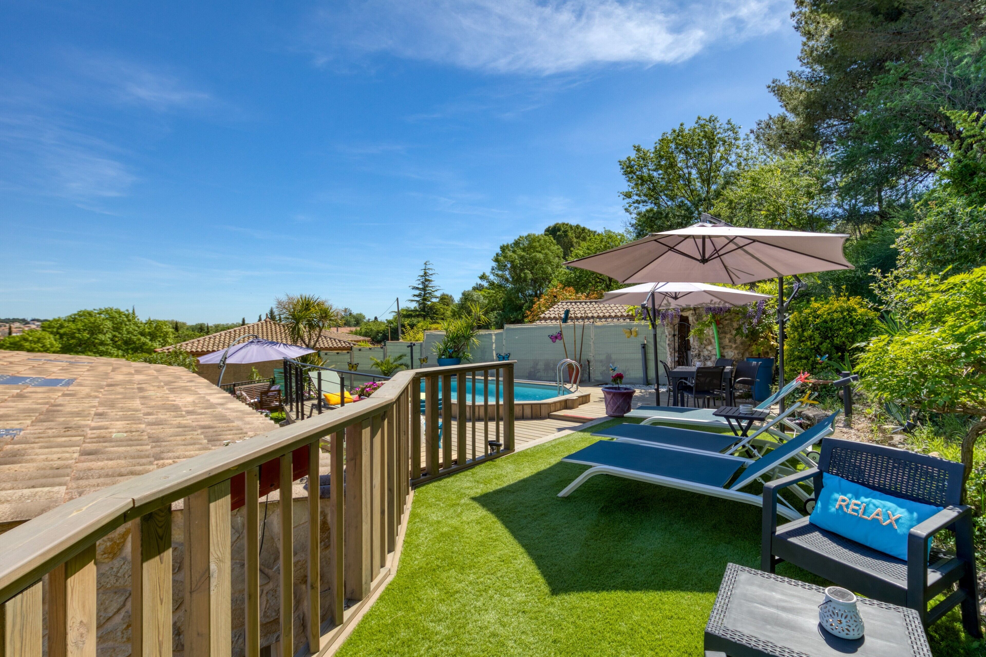 A backyard with a swimming pool, lounge chairs, and a deck.