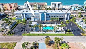 Ett hotell med en swimmingpool, en parkeringsplats och utsikt över havet.