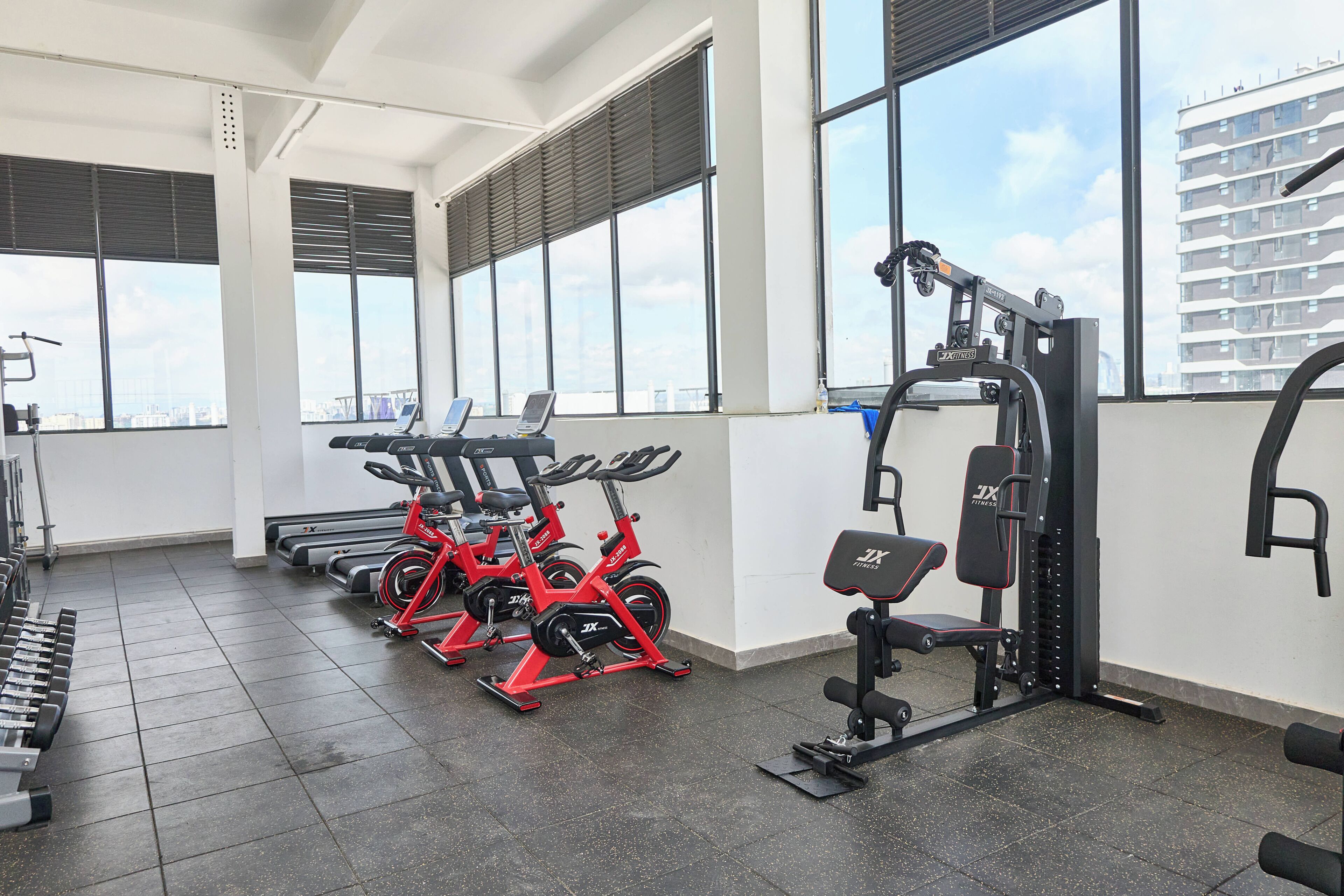 Una palestra con attrezzature per l'allenamento, ampie finestre e vista sulla città.