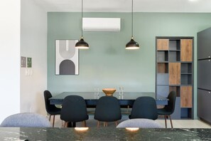 Un espace de salle à manger moderne avec une table en bois foncé, des chaises noires et des luminaires suspendus.