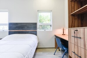 Ein Schlafzimmer mit Bett, Schreibtisch, Stuhl, Fenster und Kleiderschrank.