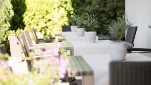 An outdoor seating area with tables and chairs, surrounded by greenery. - Room 'Zimmer 21' with Shared Pool, Shared Terrace and Wi-Fi (Merano)