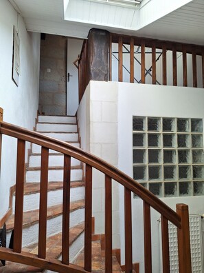 A staircase with wooden railings, a white wall, and a window with frosted glass.