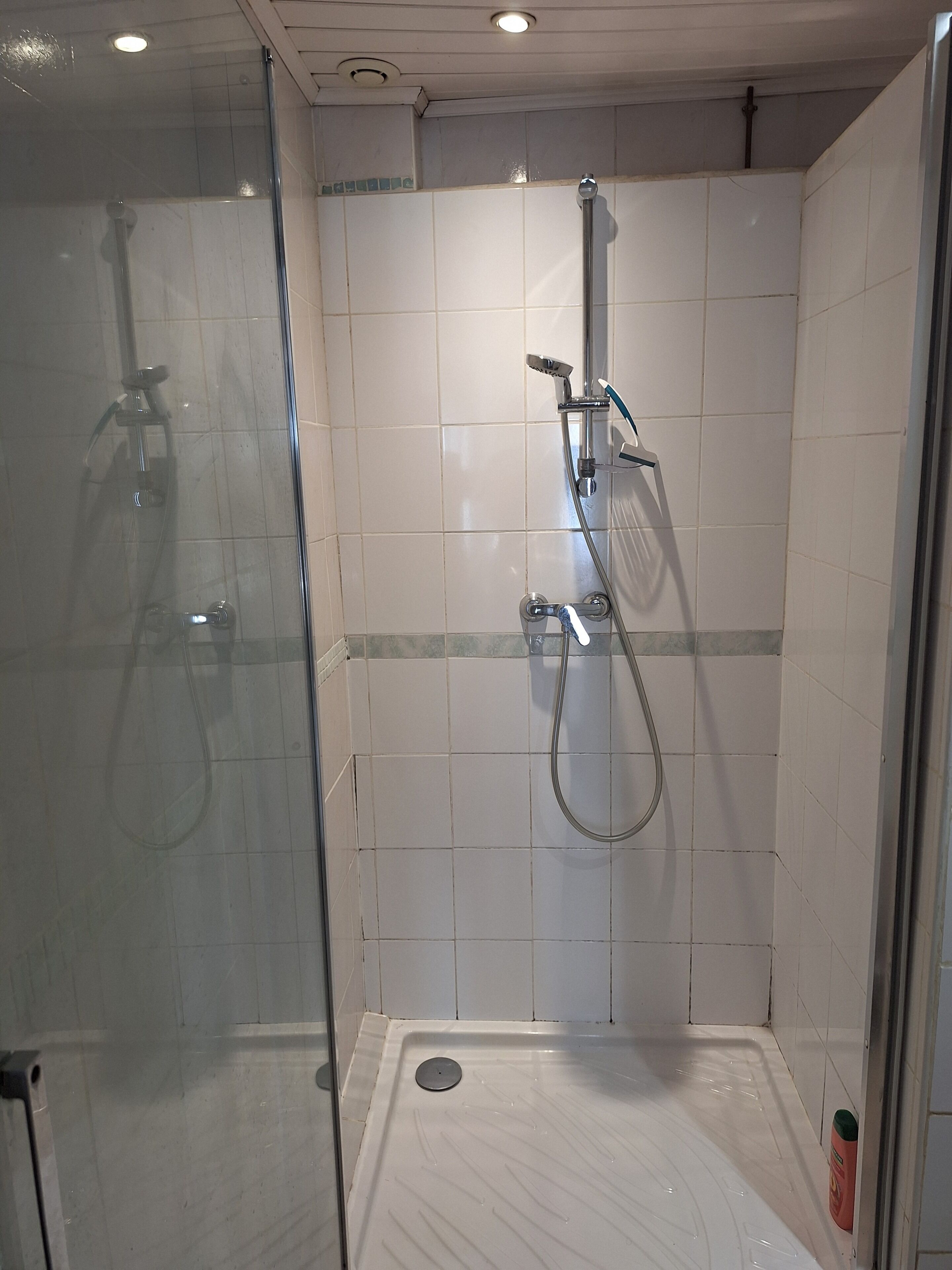 Ducha envidriada amb plat de roba de mà i aixeta fixa a la paret.