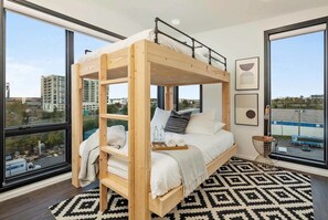 A bunk bed with a city view, a patterned rug, and a small side table. - Gulch Nashville condo with private deck & pool, sleeps 8 on VRBO (Nashville)