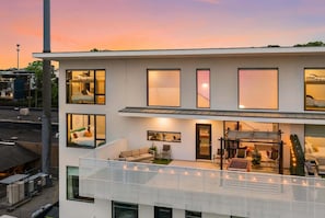 A modern multi-story building with large windows, a balcony, and a rooftop terrace. - Summer pool, skyline deck, free parking, walk to The Gulch (Nashville)