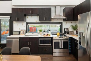 Eine moderne Küche mit dunklen Schränken, einem Edelstahl-Kühlschrank, einem eingebauten Backofen und einer Mikrowelle.