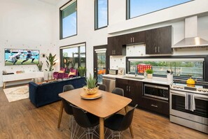 A modern kitchen with dark cabinets, a wooden dining table, and a TV mounted on the wall. - Gulch Nashville condo with private deck & pool, sleeps 8 on VRBO (Nashville)