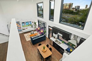 A modern apartment with a kitchen, dining area, and living room, featuring large windows and a city view. - Gulch Nashville condo with private deck & pool, sleeps 8 on VRBO (Nashville)
