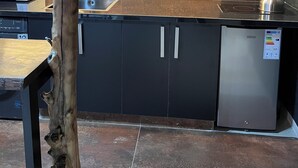 Moderni keittiö, jossa on sisäänrakennettu astianpesukone, vedenkeitin ja seinällä taideteos.