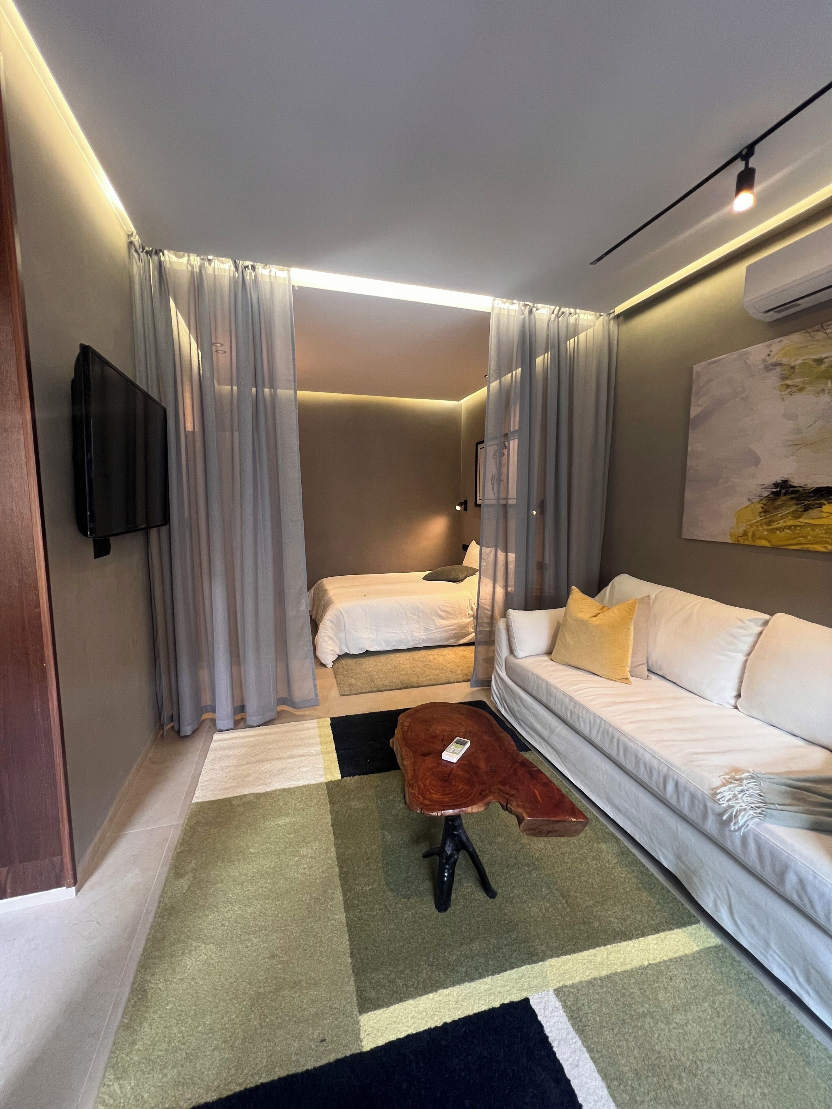 A hotel room with a bed, a sofa, a TV, and a coffee table.