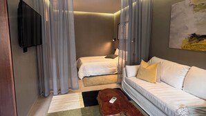 Hotellihuone, jossa on sänky, sohva, televisio ja sohvapöytä.