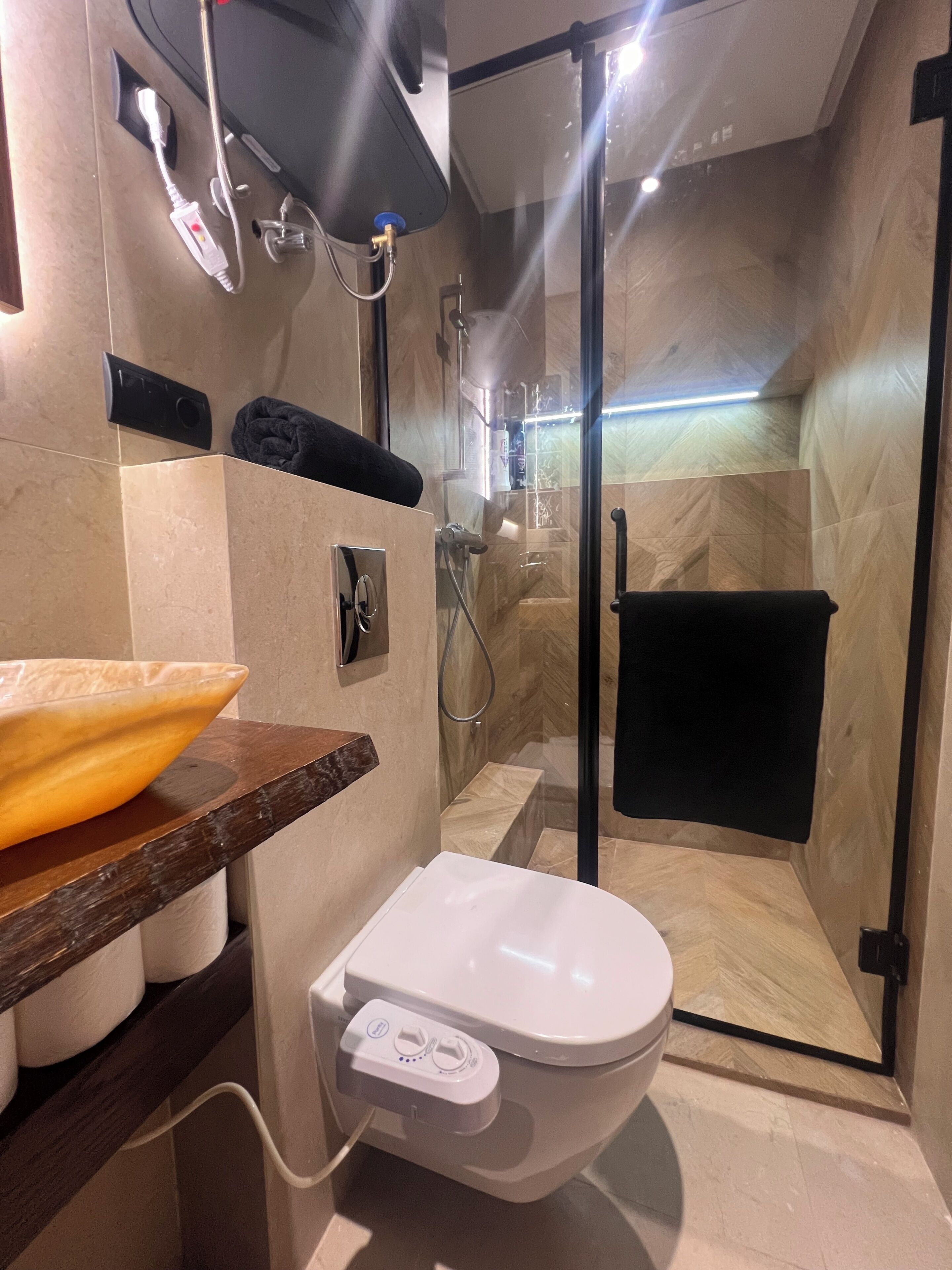 Et moderne badeværelse med toilet, bruser og et glasafskærmet bruseområde.
