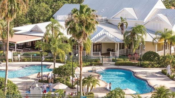 A resort with multiple swimming pools, palm trees, and a covered patio area. - Orlando | Couples Theme Park Retreat | Pool + Hot Tub (Orlando)