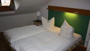 Un dormitorio con una cama grande, una mesita de noche, una lámpara y vistas al exterior a través de una ventana.