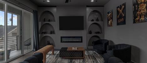 A modern living room with a flat-screen TV, comfortable seating, and a dog.