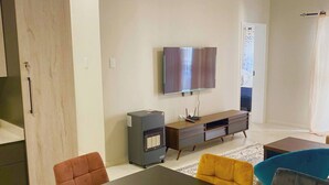 Una sala de estar moderna con una mesa de comedor, sofás, un televisor y un calefactor.