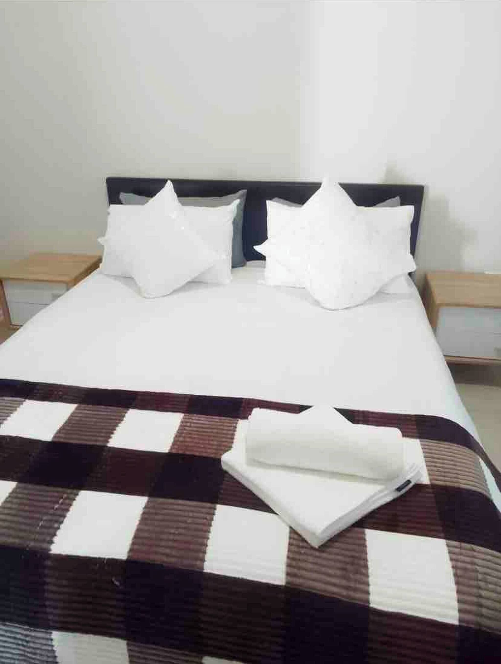 A bed with a checkered bedspread, two pillows, and a headboard.