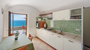 Una cocina con vistas al mar, una mesa de comedor con una planta y un balcón con una silla.