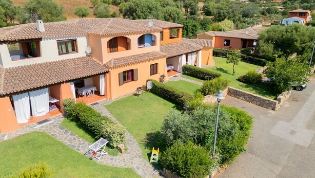 Un edificio a più piani con tetto in tegole, un cortile con prato e un vialetto in pietra.