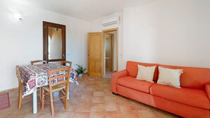 Un soggiorno con un tavolo da pranzo, sedie, un divano e una porta in legno.