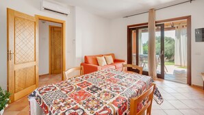 Una camera da letto con un letto, un divano, un tavolo da pranzo e una porta vetrata scorrevole che dà su un'area esterna.