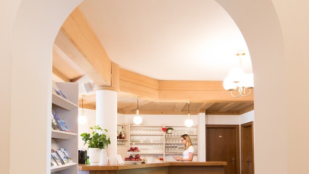 An interior with a reception desk, shelving with books and decorative items, a wooden ceiling, and pendant lighting. - Room 'Stanza 23' with Shared Pool, Shared Terrace and Wi-Fi (Merano)