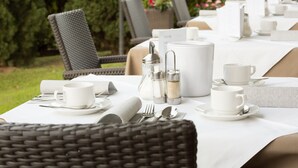 A table set for dining outdoors with wicker chairs, white tablecloth, and silverware. - Room 'Stanza 23' with Shared Pool, Shared Terrace and Wi-Fi (Merano)
