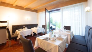A dining area with tables set for service, a sofa, and a view through a glass door. - Room 'Stanza 23' with Shared Pool, Shared Terrace and Wi-Fi (Merano)