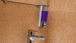 A bathroom with a white sink, chrome faucet, and a mirror with a towel holder. - Varad International Hotel and Banquet (Alapur)