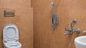 A bathroom with a toilet, a shower, and a sink. - Varad International Hotel and Banquet (Alapur)