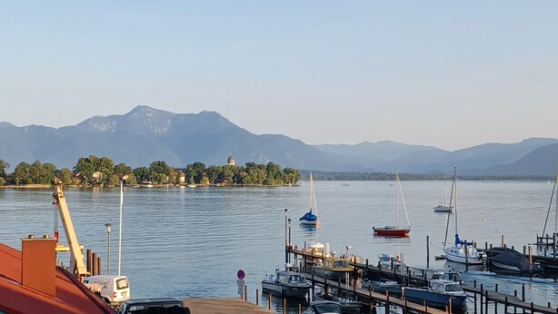 Ein Yachthafen mit vertäuten Booten, ein klarer Himmel und Berge im Hintergrund.