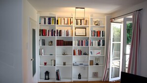 Ein geräumiger Raum mit einem großen Bücherregal voller Bücher, einem gerahmten Bild und einer Teekanne.