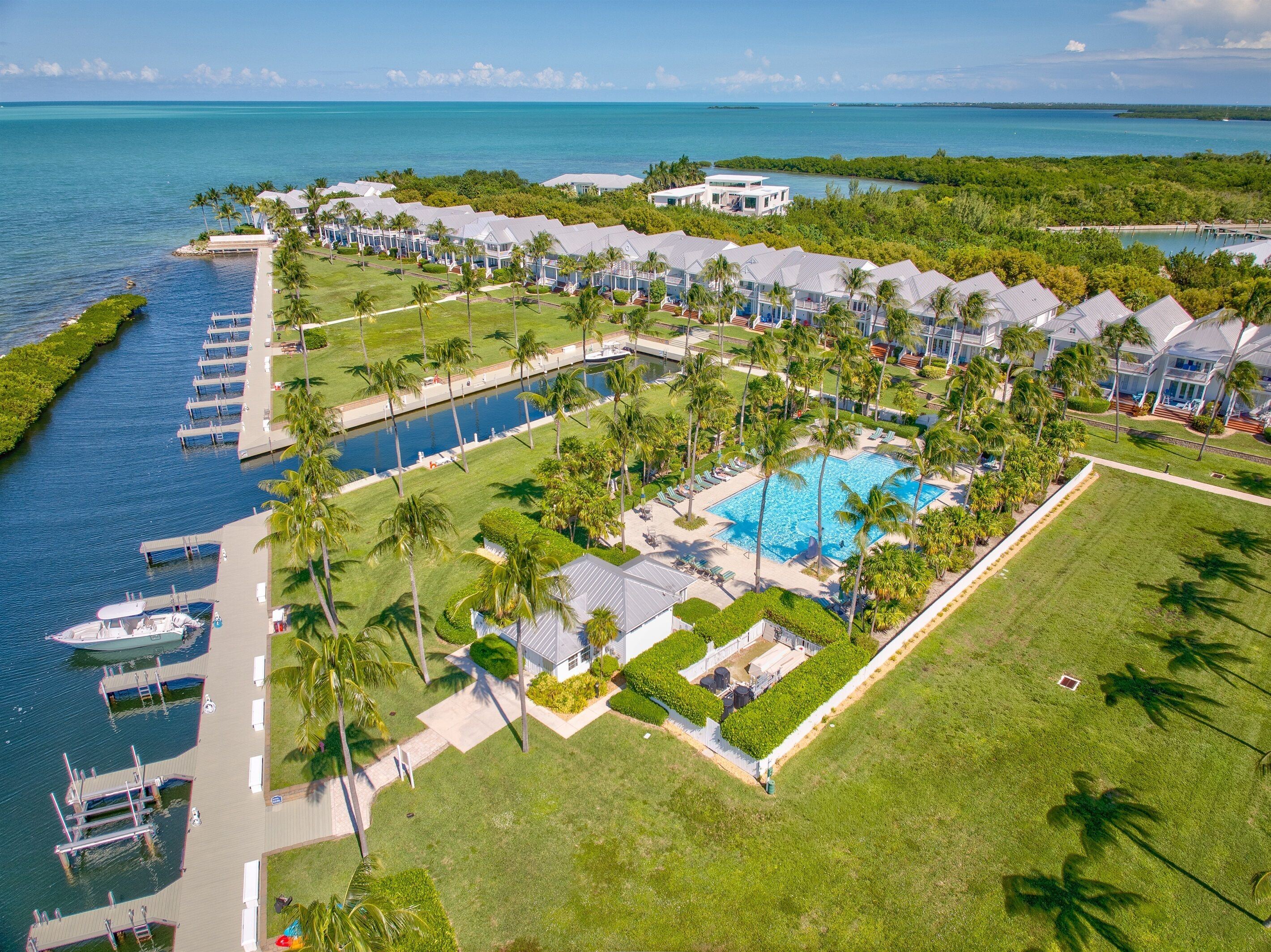 An aerial view of a resort with a swimming pool, docked boats, and a marina.