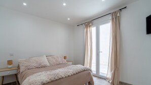 Una camera da letto con un letto, comodini, una TV e una porta a vetri scorrevoli.