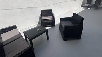 Une terrasse sur le toit, aménagée avec des meubles en osier, une petite table et une prise de courant.
