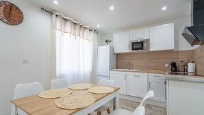 Una cucina moderna con mobili bianchi, un forno a microonde e un tavolo da pranzo in legno con tovagliette.