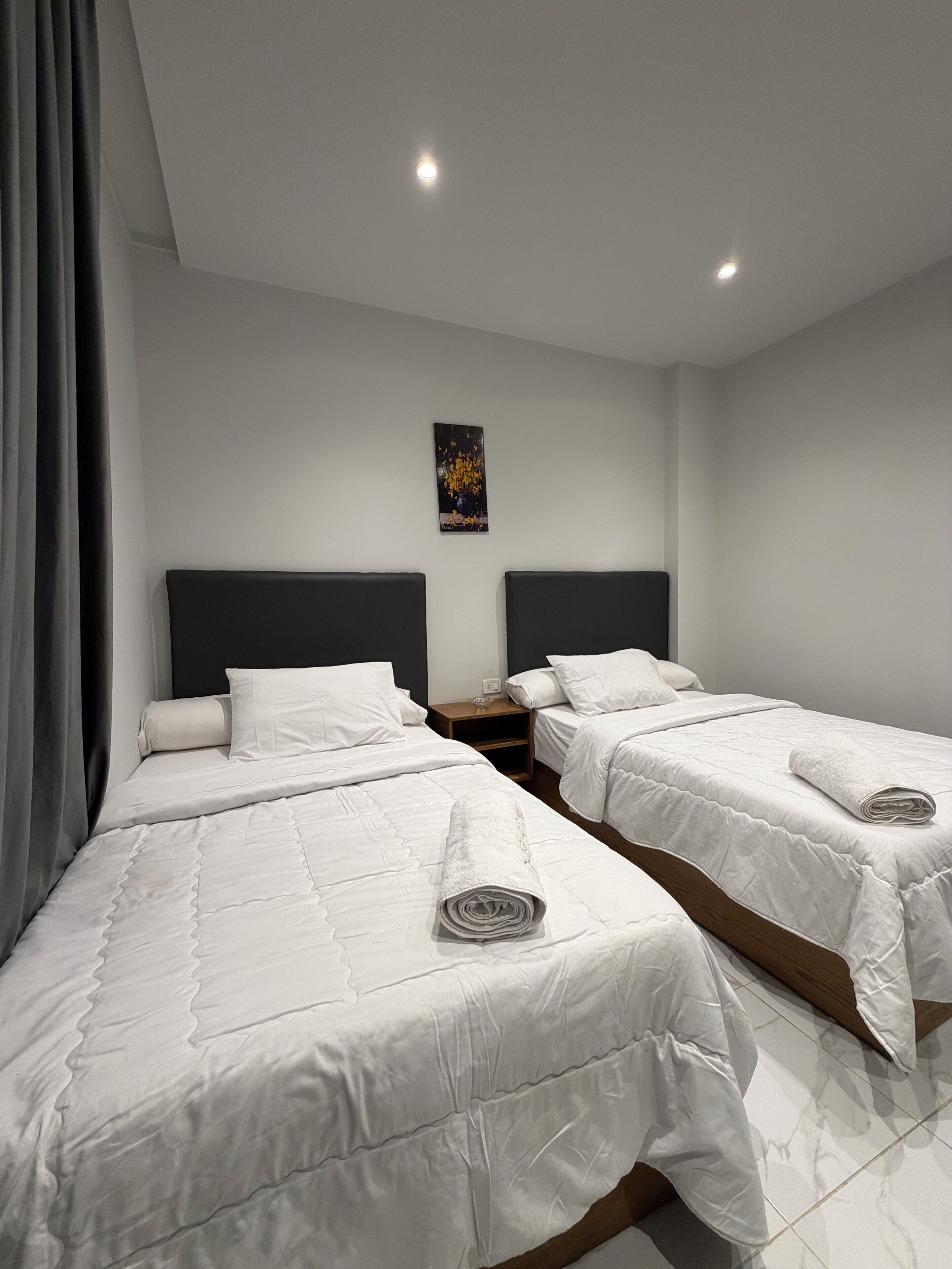 Une chambre d’hôtel avec deux lits, une table de chevet et un tableau au mur.