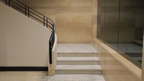 Eine Treppe mit schwarzer Geländer, Marmorstufen und einer Glaswand auf einer Seite.