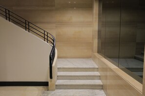 A staircase with a black railing, marble steps, and a glass wall on one side. - DHB STAYS DOWNTOWN (Cairo)