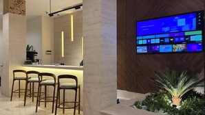 Ein moderner Empfangsbereich mit Bar, Sitzgelegenheiten, einem digitalen Display und einer kleinen Indoor-Gartenanlage.