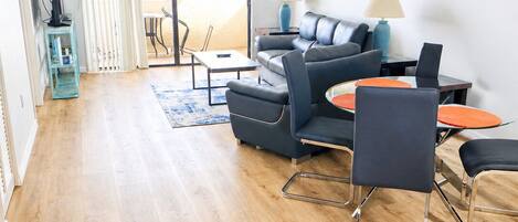 Ein modernes Wohnzimmer mit Sofa, Sesseln, einem Couchtisch und einem Fernsehschrank.