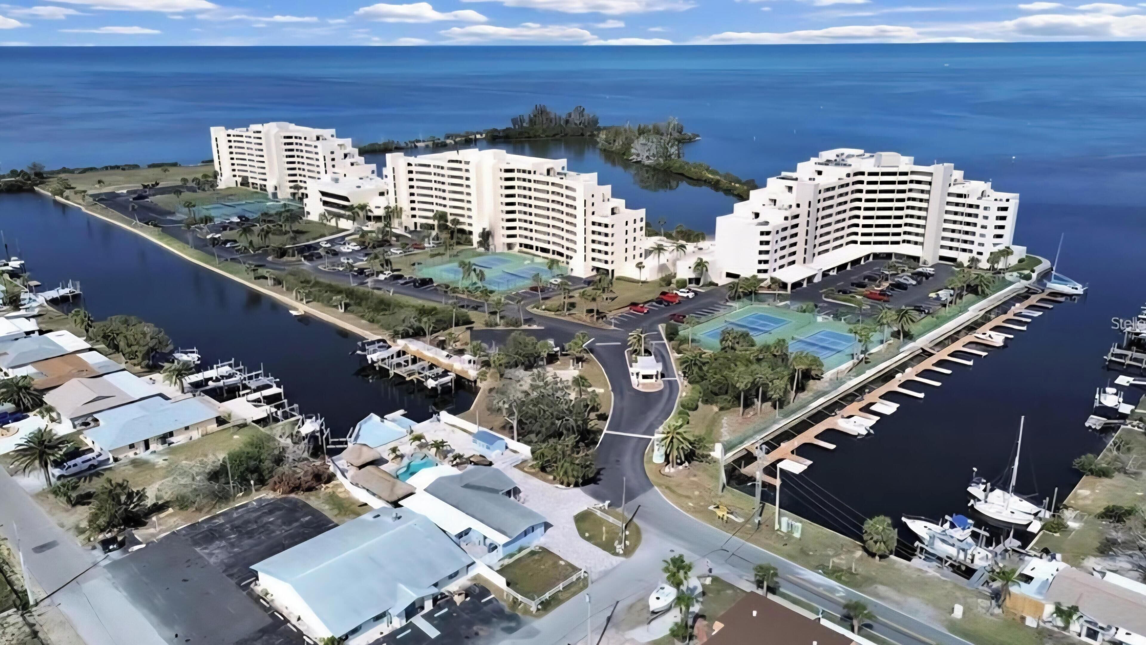 A waterfront hotel with multiple buildings, a marina, and a tennis court.