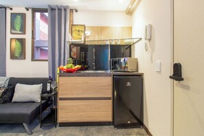 A compact living space with a kitchenette, a sofa, a small refrigerator, and a dining area. - Ayamonte 306 Loft (Medellín)