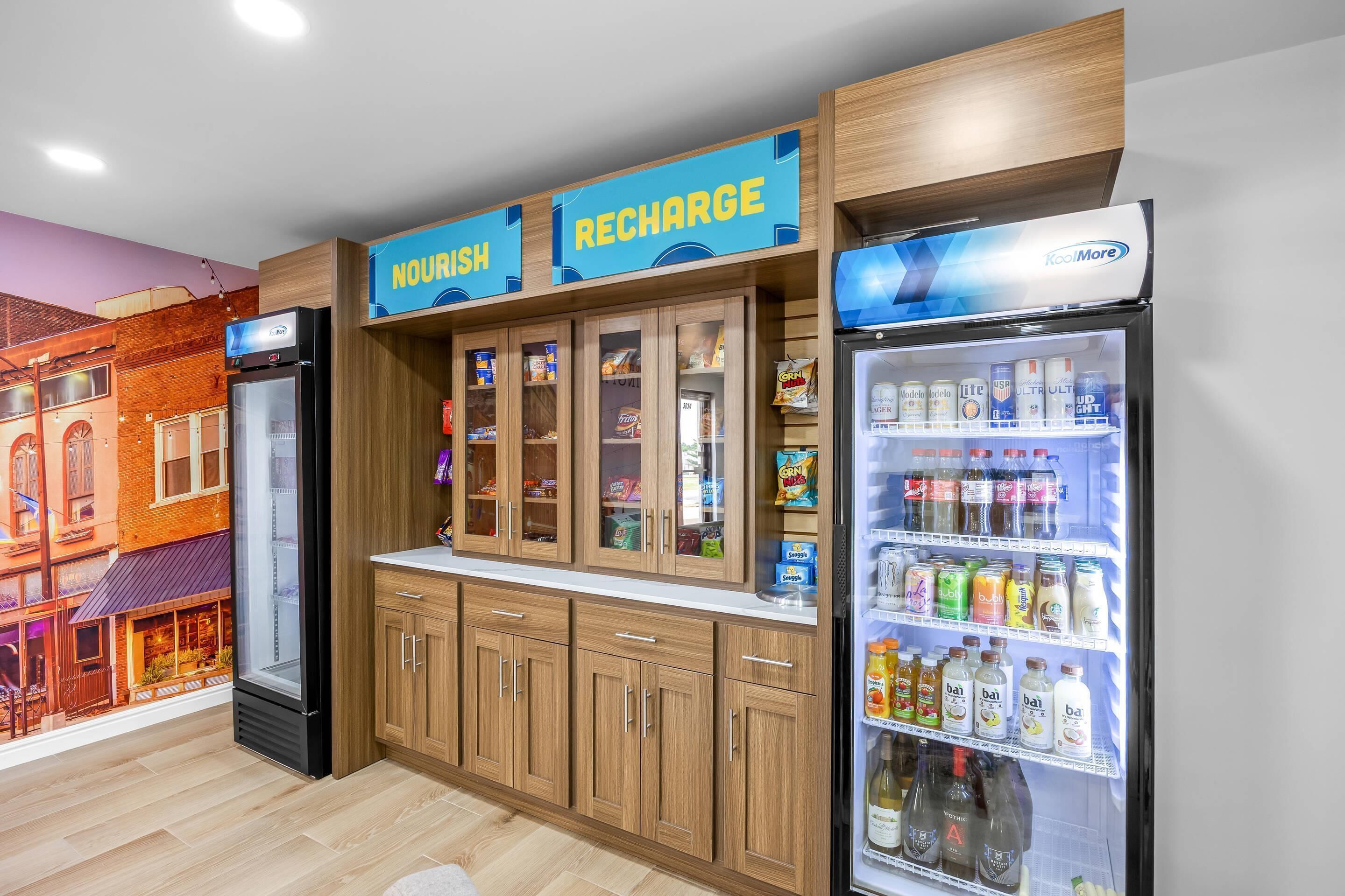 A kitchenette with a refrigerator, cabinets, and a wall mural.