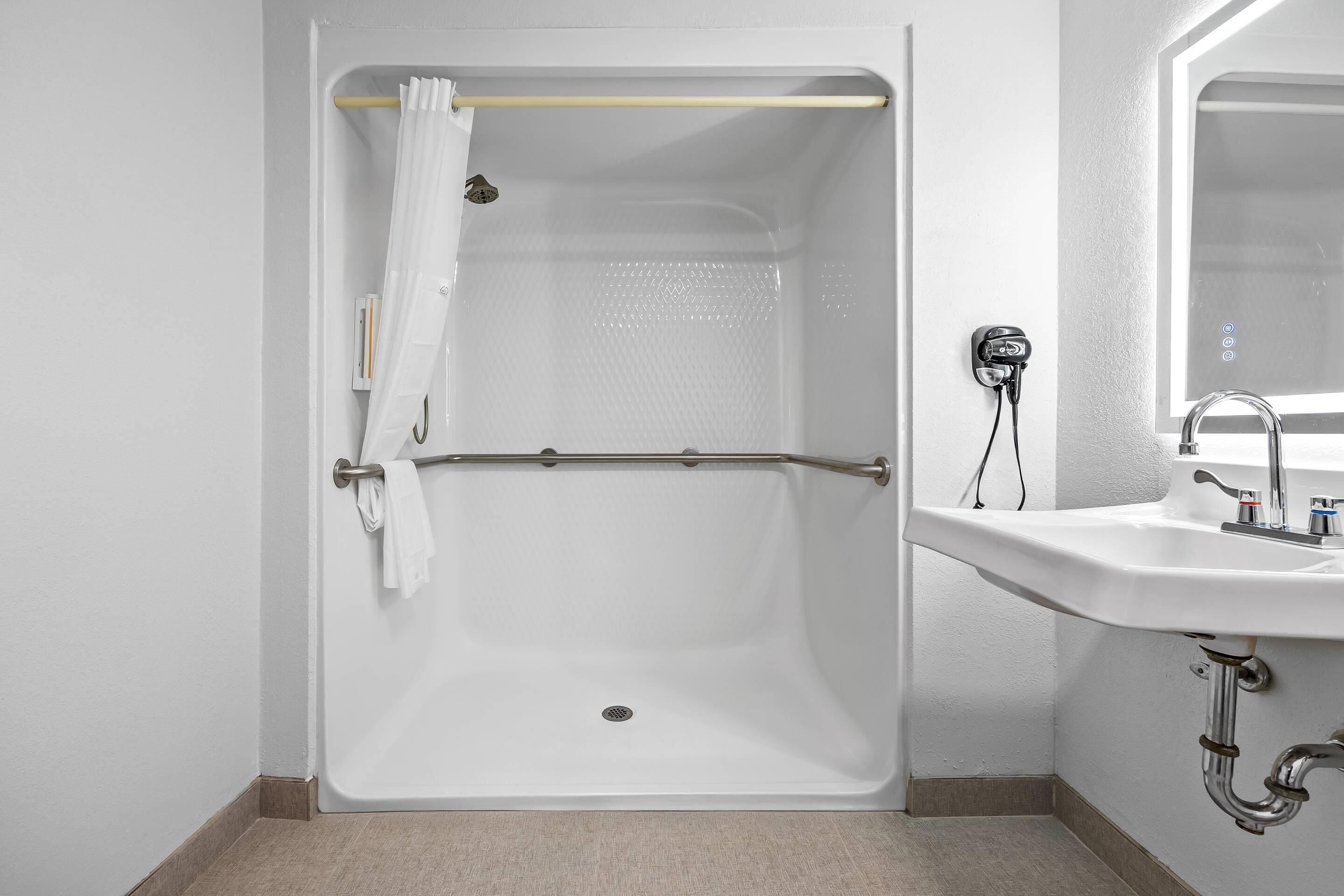 A bathroom with a walk-in shower, a white sink, and a mirror.